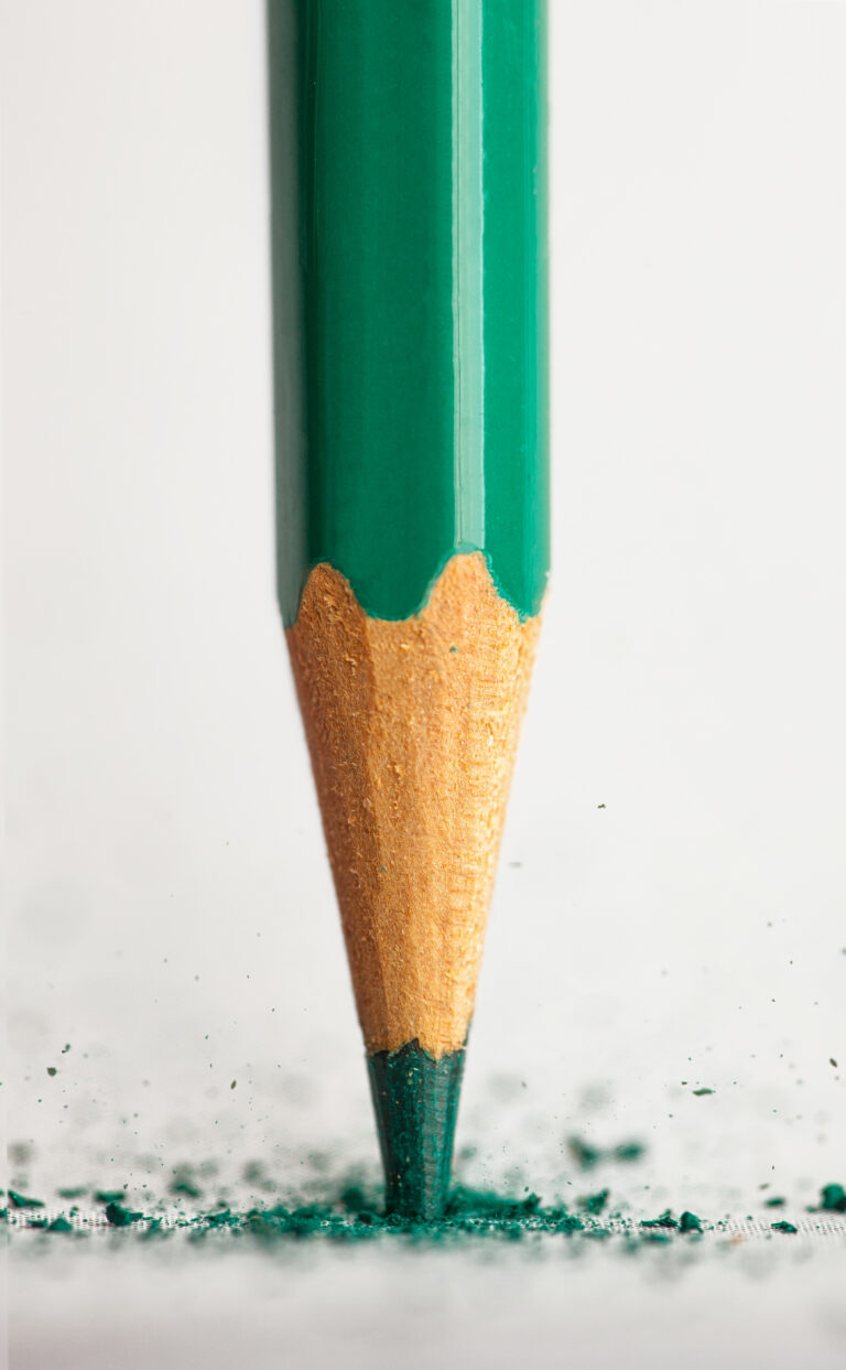 Gros plan d’un crayon vert taillé en train de tracer une ligne