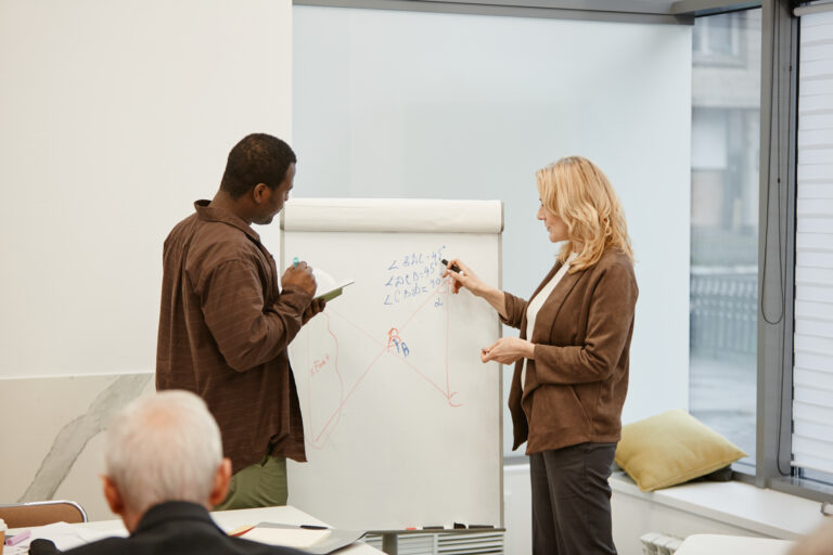 Formateur expliquant un concept technique sur un tableau blanc pendant une session de formation