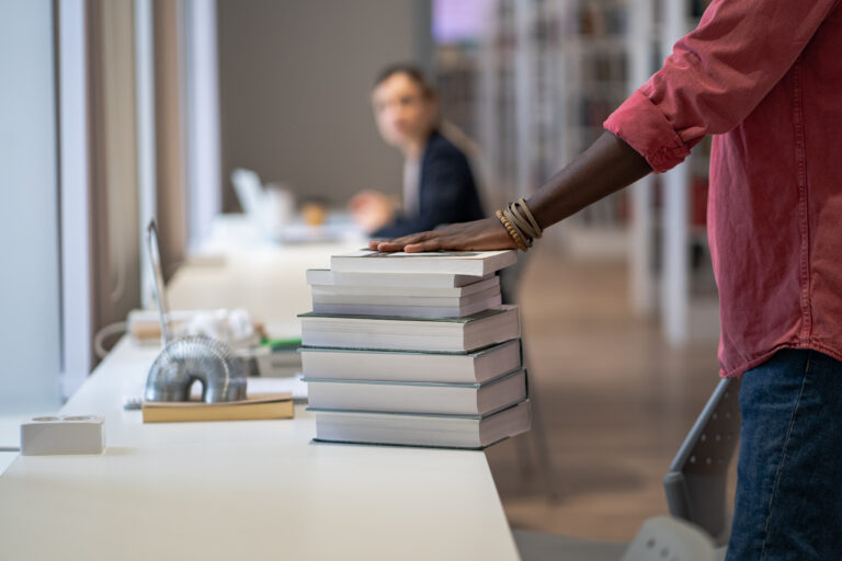 Main posée sur une pile de livres dans un environnement d’apprentissage pour adultes